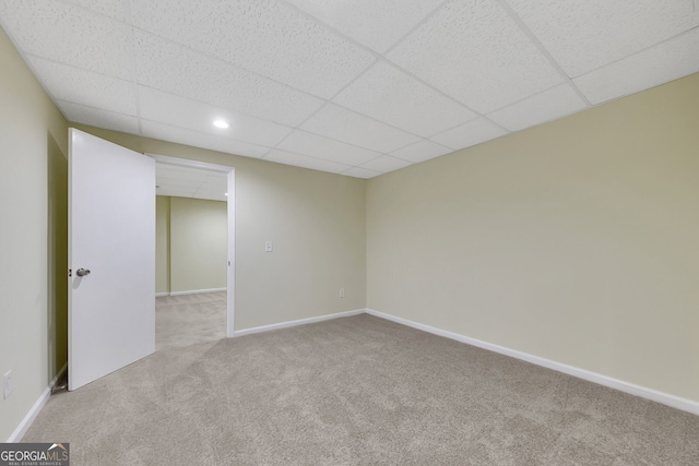 spare room featuring light carpet and a paneled ceiling