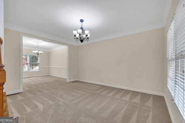 carpeted spare room featuring ornamental molding and a notable chandelier