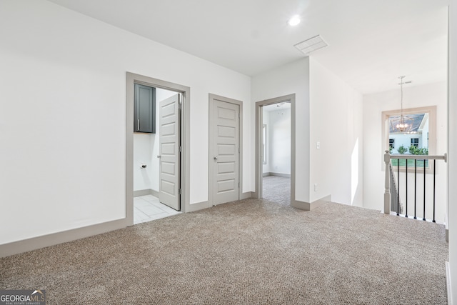 unfurnished bedroom featuring light carpet and a notable chandelier