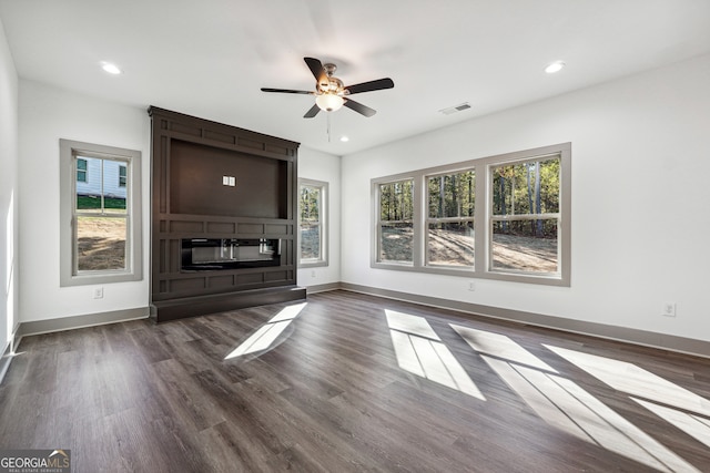 unfurnished living room with dark wood-type flooring, plenty of natural light, and ceiling fan