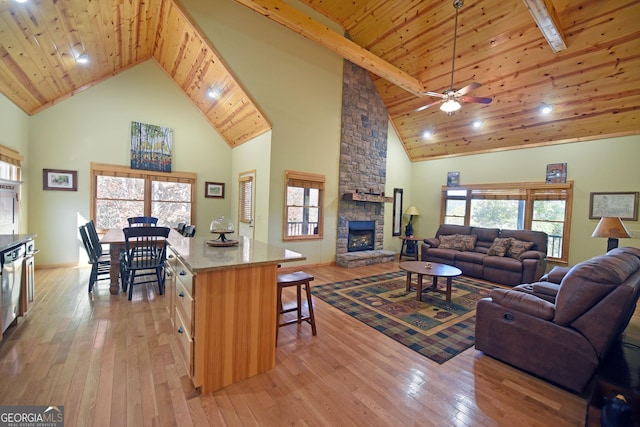 living room with a stone fireplace, a wealth of natural light, light hardwood / wood-style flooring, and high vaulted ceiling