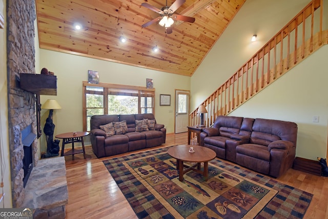 living room featuring ceiling fan, high vaulted ceiling, light hardwood / wood-style flooring, wooden ceiling, and a fireplace