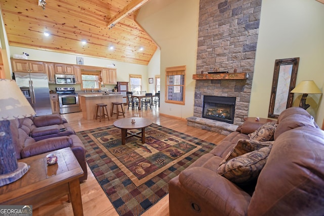 living room featuring high vaulted ceiling, beamed ceiling, wooden ceiling, a fireplace, and light hardwood / wood-style floors