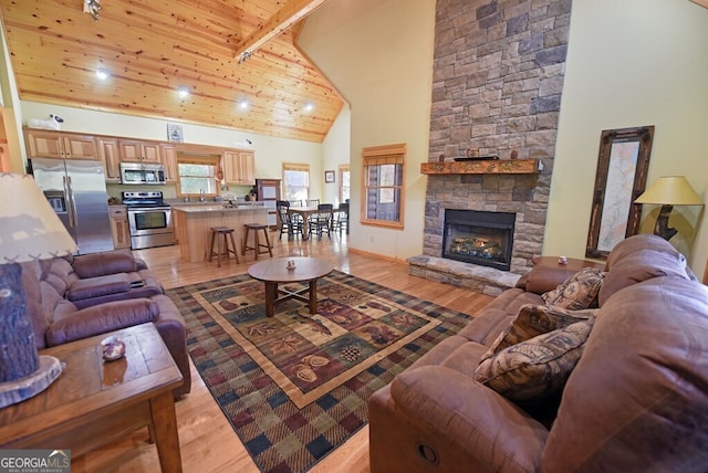 living room featuring sink, high vaulted ceiling, light wood-type flooring, wooden ceiling, and beam ceiling