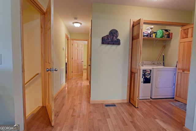 clothes washing area with independent washer and dryer and light hardwood / wood-style flooring