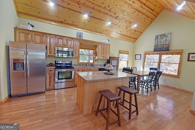 kitchen featuring appliances with stainless steel finishes, sink, a center island, light stone countertops, and wooden ceiling