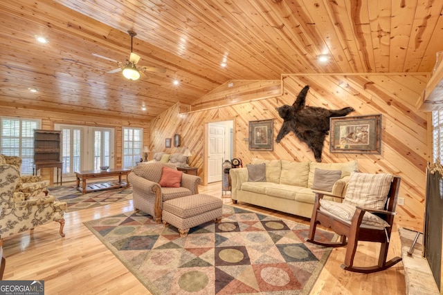 living room featuring light wood finished floors, lofted ceiling, wood ceiling, wood walls, and ceiling fan