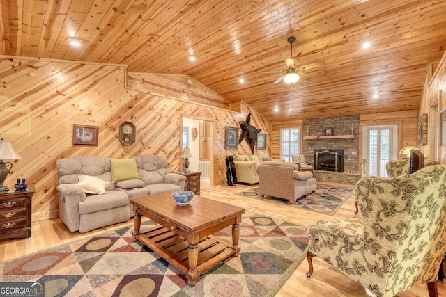 living area with wooden ceiling, wooden walls, a fireplace, wood finished floors, and vaulted ceiling