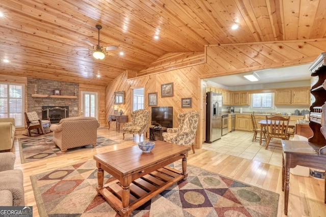 living room with wood walls, wood ceiling, vaulted ceiling, and a wealth of natural light