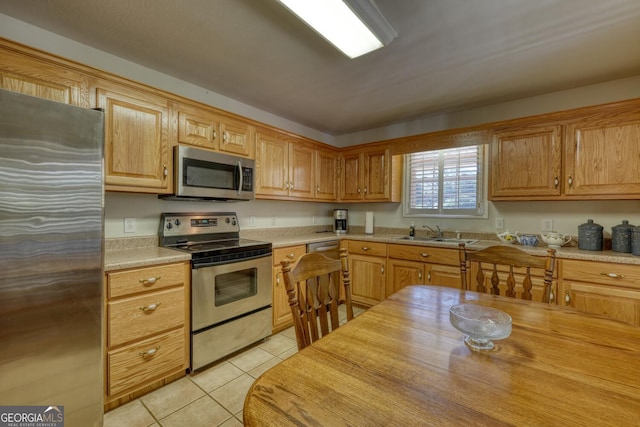 kitchen featuring stainless steel appliances, a sink, and light tile patterned flooring