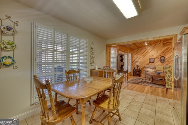 dining area featuring light tile patterned floors and wooden walls