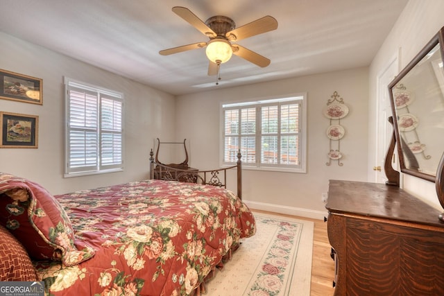 bedroom with baseboards, multiple windows, a ceiling fan, and light wood-style floors