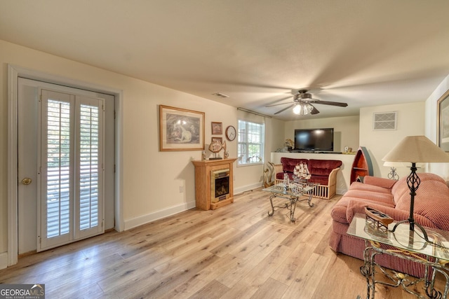 living room featuring light wood-type flooring, visible vents, a fireplace, and baseboards