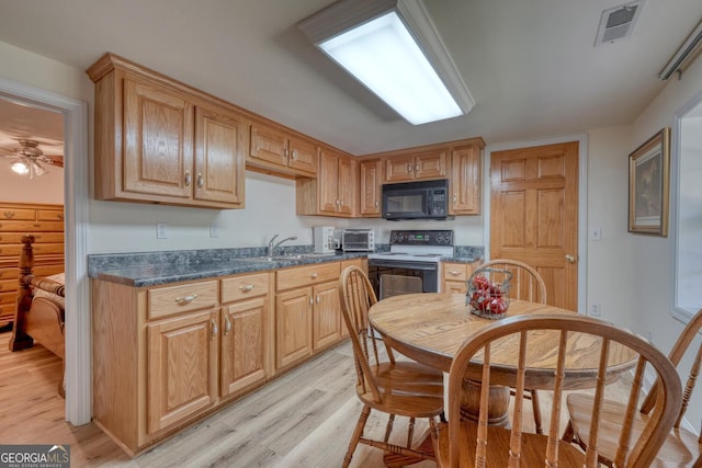 kitchen with black microwave, electric range, visible vents, light wood-style floors, and dark countertops