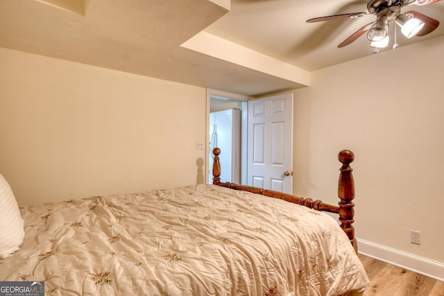 bedroom with a ceiling fan, light wood-type flooring, a textured ceiling, and baseboards