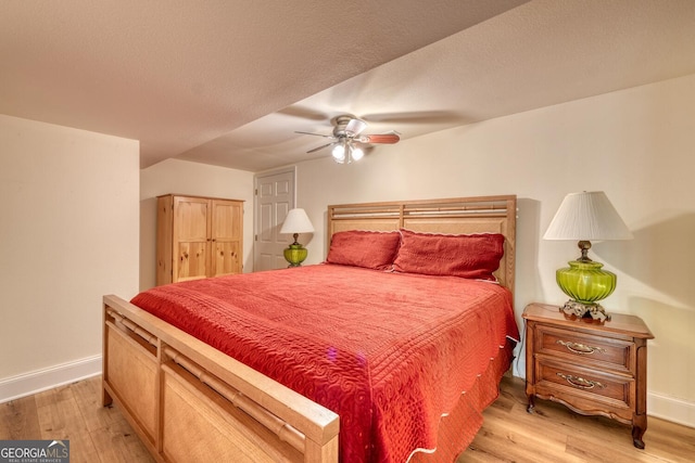 bedroom featuring light wood-style floors, ceiling fan, a textured ceiling, and baseboards