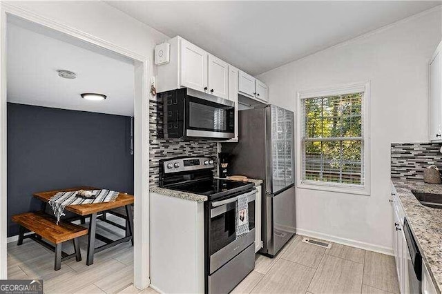 kitchen with stainless steel appliances, sink, light stone countertops, white cabinetry, and tasteful backsplash