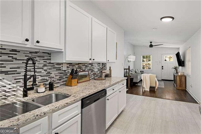 kitchen with sink, stainless steel dishwasher, white cabinets, light stone counters, and light hardwood / wood-style flooring