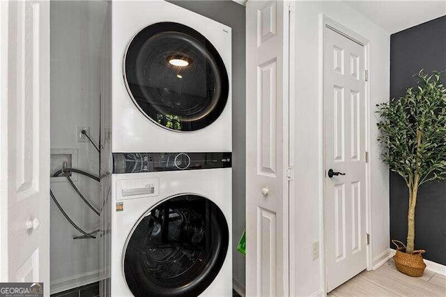 laundry room with light hardwood / wood-style flooring and stacked washing maching and dryer