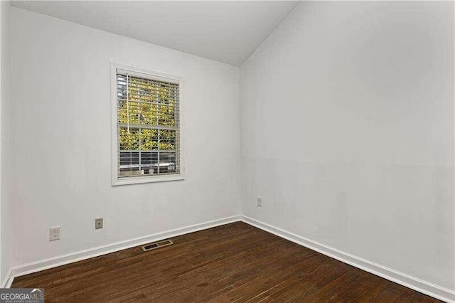 empty room featuring vaulted ceiling and hardwood / wood-style flooring