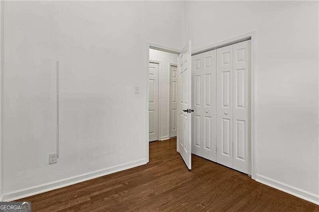 unfurnished bedroom featuring a closet and dark wood-type flooring