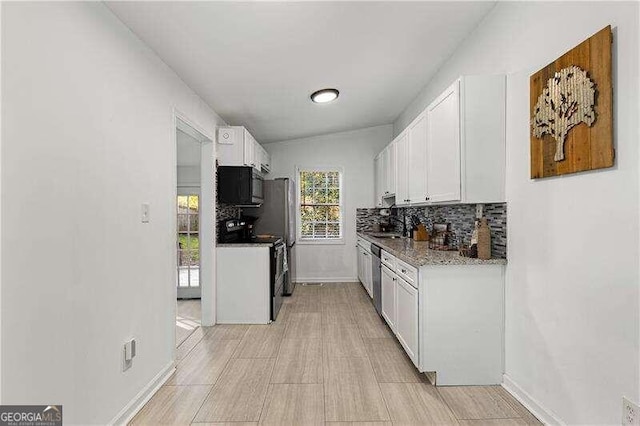 kitchen featuring decorative backsplash, white cabinetry, light stone countertops, vaulted ceiling, and black appliances