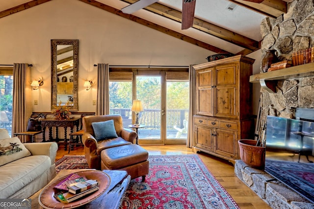 living room with light hardwood / wood-style flooring, a healthy amount of sunlight, beamed ceiling, and high vaulted ceiling