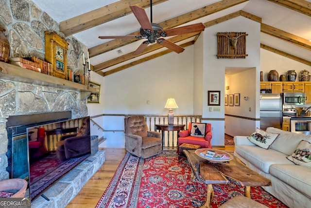 living room featuring a stone fireplace, ceiling fan, beam ceiling, high vaulted ceiling, and light hardwood / wood-style flooring