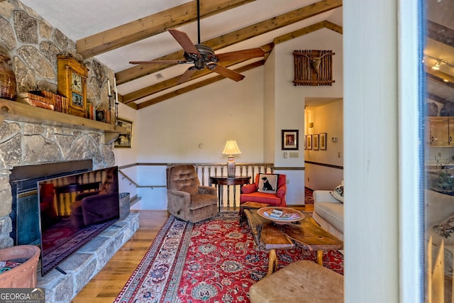 living room with ceiling fan, hardwood / wood-style flooring, vaulted ceiling with beams, and a fireplace