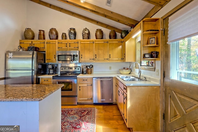 kitchen with appliances with stainless steel finishes, lofted ceiling with beams, sink, and light wood-type flooring