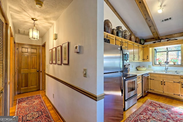 kitchen featuring stainless steel appliances, sink, lofted ceiling with beams, decorative light fixtures, and light hardwood / wood-style floors