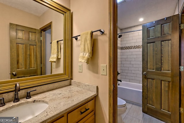 full bathroom with tiled shower / bath, vanity, toilet, and tile patterned floors