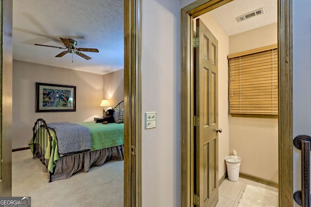 bedroom with a textured ceiling, light colored carpet, and ceiling fan