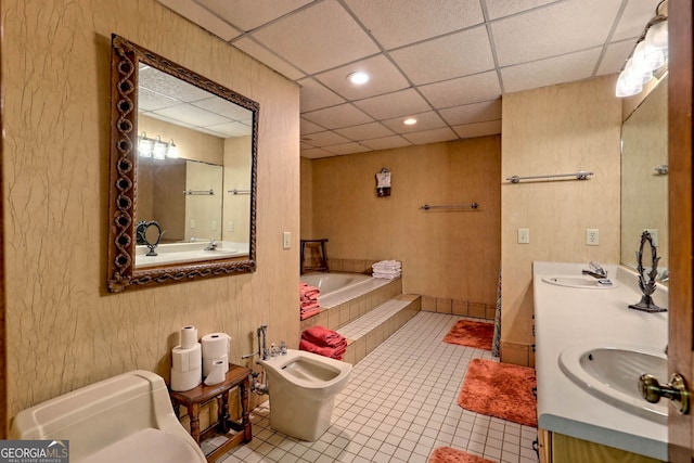 bathroom with toilet, a bidet, a bath, vanity, and a drop ceiling