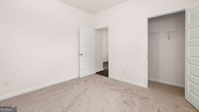 unfurnished bedroom with dark colored carpet and a closet