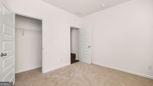 unfurnished bedroom featuring a closet and light carpet