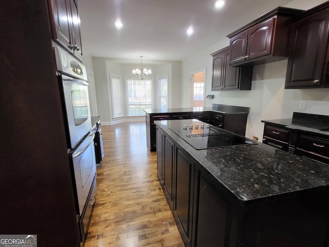 kitchen featuring an inviting chandelier, black electric cooktop, dark brown cabinets, light wood-style floors, and pendant lighting