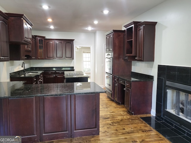 kitchen with dark wood finished floors, glass insert cabinets, a peninsula, a fireplace, and open shelves