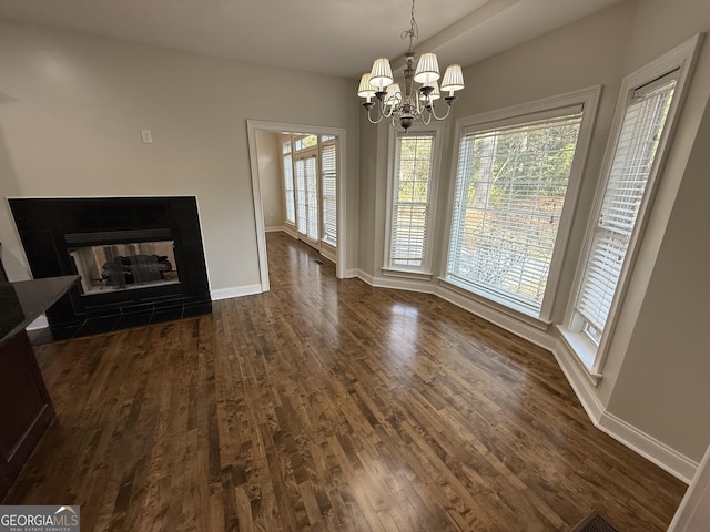 unfurnished living room with a notable chandelier, a fireplace, baseboards, and dark wood-type flooring