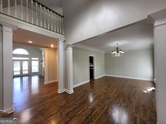 empty room featuring ornate columns, baseboards, dark wood finished floors, and ornamental molding