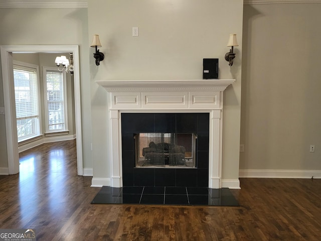 details with a tiled fireplace, baseboards, and wood finished floors