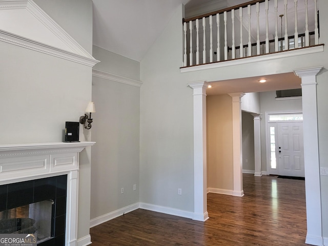 unfurnished living room with ornate columns, baseboards, dark wood-style floors, and a tile fireplace