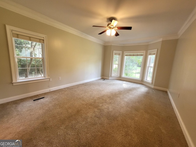 carpeted spare room featuring baseboards, a ceiling fan, visible vents, and crown molding