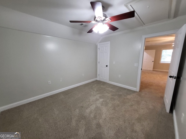 unfurnished bedroom featuring lofted ceiling, carpet floors, a ceiling fan, baseboards, and attic access