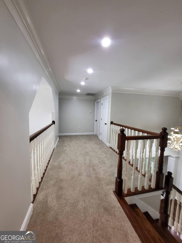 hall featuring carpet, ornamental molding, baseboards, and an upstairs landing