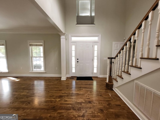 foyer entrance featuring dark wood-type flooring, a high ceiling, baseboards, ornamental molding, and stairway