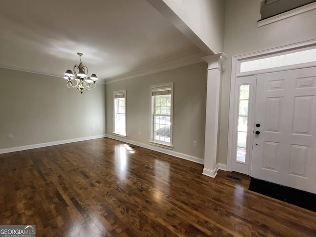 foyer featuring baseboards, dark wood-style floors, crown molding, ornate columns, and a chandelier