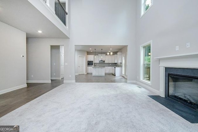 unfurnished living room featuring a towering ceiling