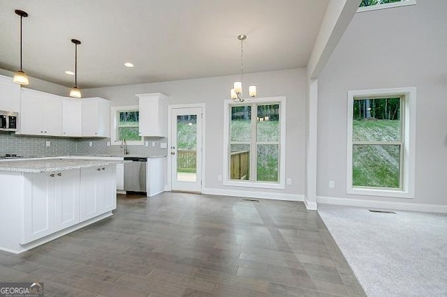 kitchen featuring white cabinets, decorative light fixtures, light stone countertops, and appliances with stainless steel finishes