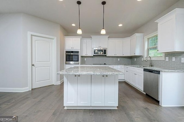 kitchen with white cabinets, a center island, hanging light fixtures, and appliances with stainless steel finishes